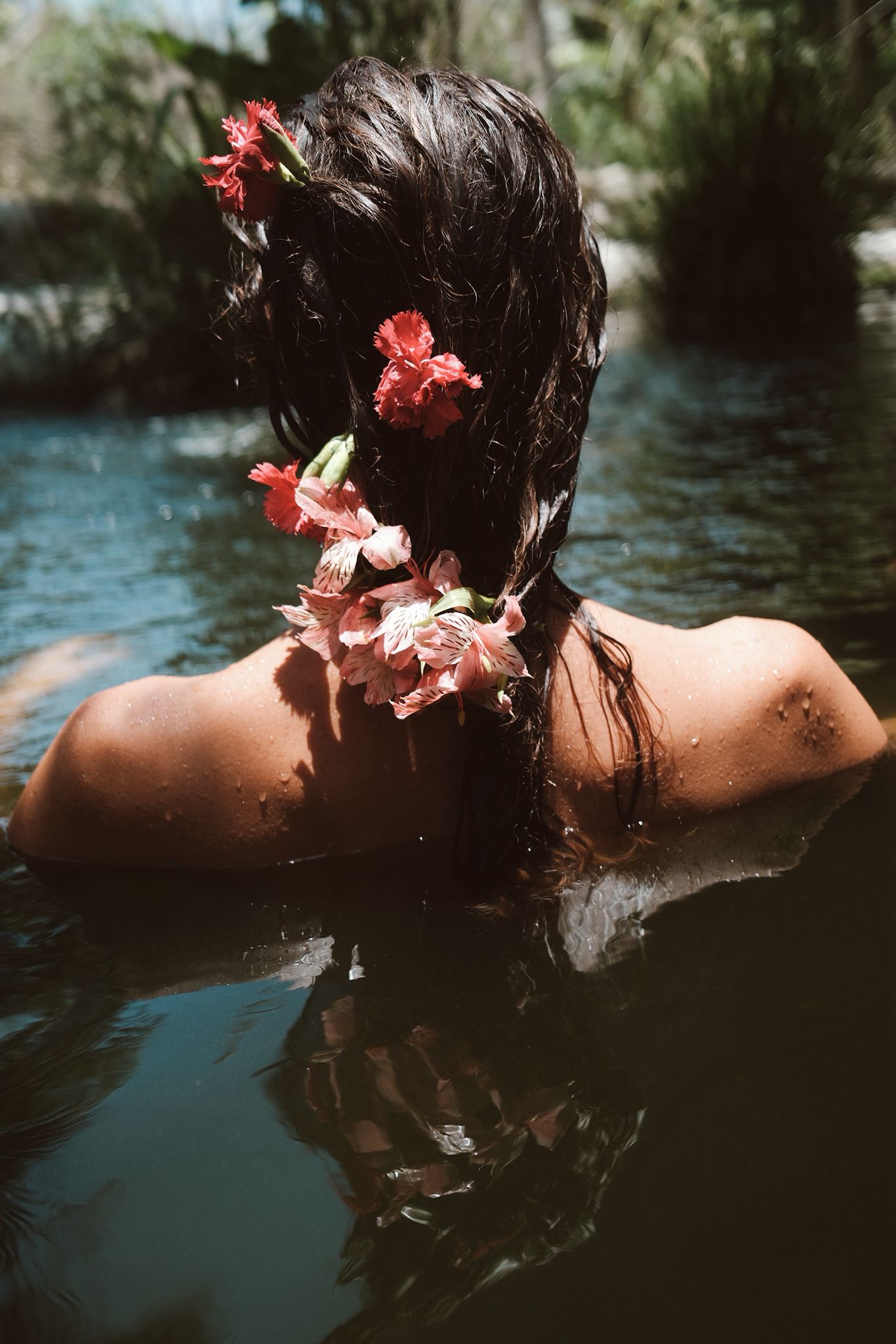 Una mujer flotando en el regazo de flores — agua, pétalos rojos en el cabello mojado
